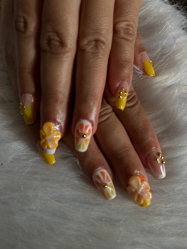 Pose Américaine Gel X jaune et orange avec fleurs 3D façon agrumes et strass dorés