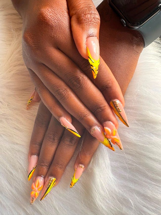 Pose Américaine Gel X jaune et noir façon tigre avec fleurs oranges et strass dorés