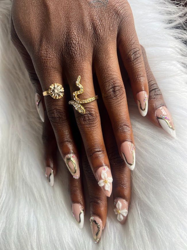 Pose Américaine Gel X amande nude avec liseré doré, fleurs 3D blanches et strass