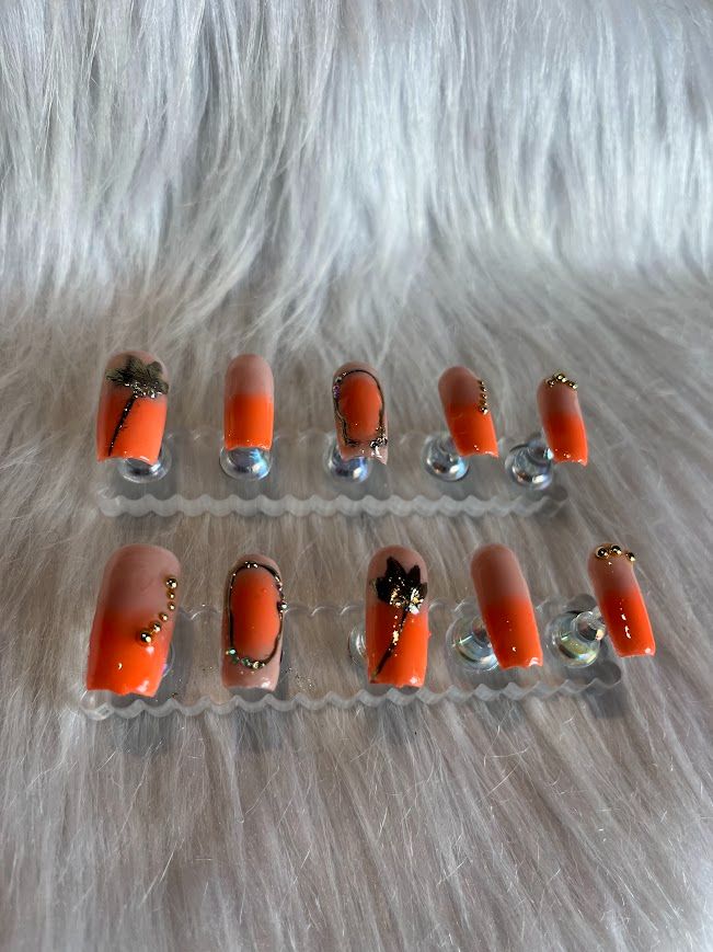 Modèle Press On Nails Orange Tropical avec nail art noir et doré